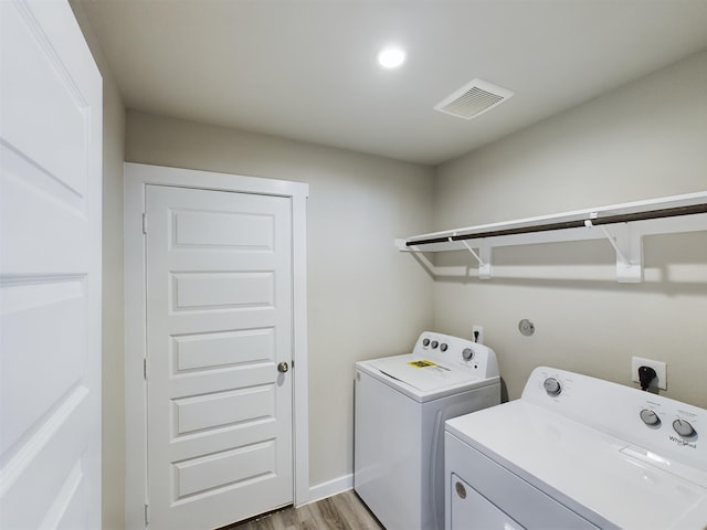 laundry area featuring washing machine and dryer and light hardwood / wood-style floors