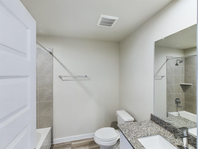 full bathroom featuring tiled shower / bath, vanity, wood-type flooring, and toilet