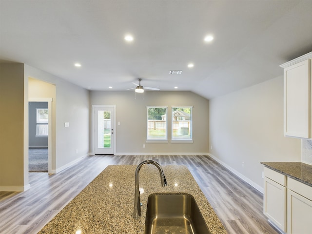 kitchen with a healthy amount of sunlight, sink, white cabinets, and dark stone counters