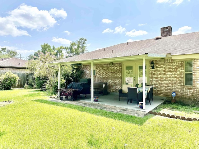 rear view of house featuring a lawn, a patio area, and french doors