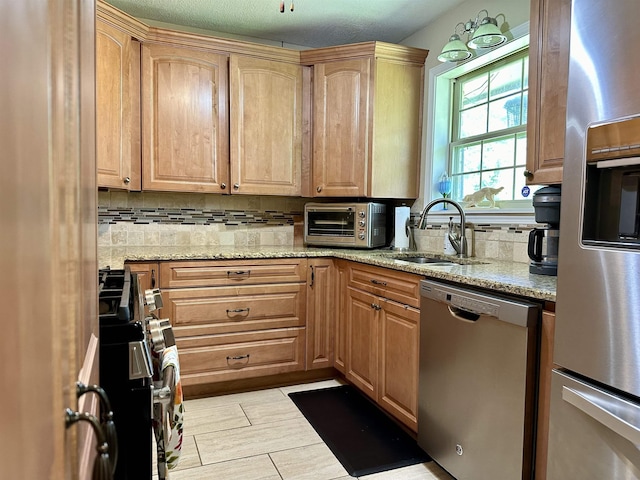 kitchen featuring appliances with stainless steel finishes, tasteful backsplash, light stone counters, and sink