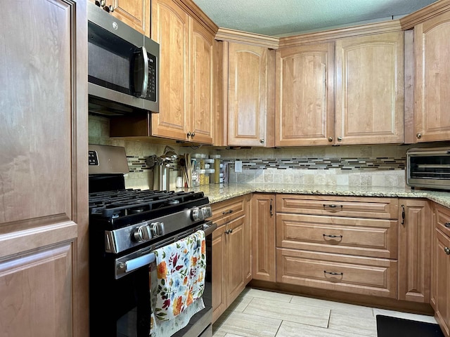 kitchen featuring decorative backsplash, appliances with stainless steel finishes, and light stone counters