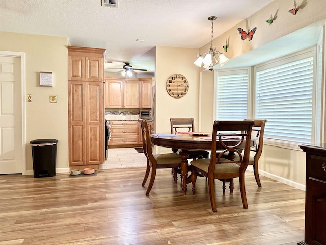 dining area with ceiling fan with notable chandelier and light hardwood / wood-style floors