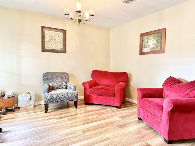 living area with light hardwood / wood-style flooring and a notable chandelier