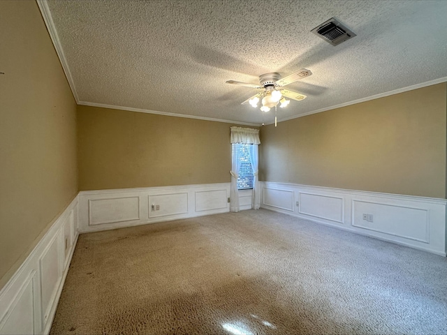 carpeted spare room with ceiling fan, ornamental molding, and a textured ceiling