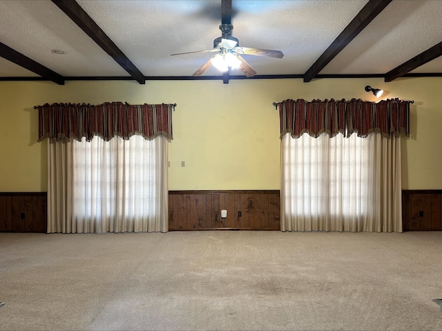 carpeted spare room featuring plenty of natural light, a textured ceiling, and beam ceiling