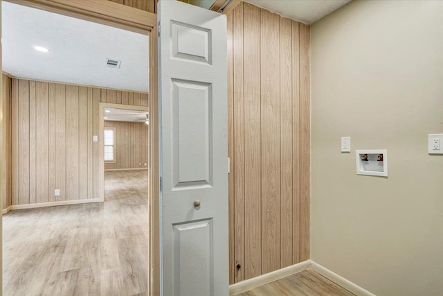 washroom with washer hookup, light wood-type flooring, and wooden walls