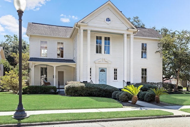 neoclassical home featuring a porch and a front lawn