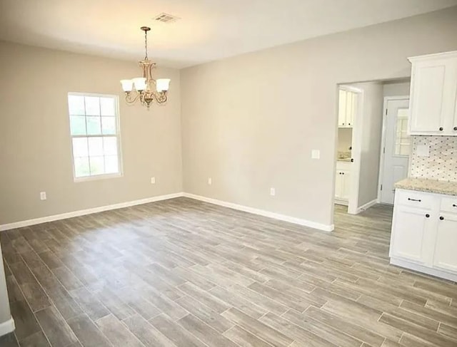 7090 Carroll Ln, Beaumont, TX 77713 - unfurnished dining area with a chandelier, light wood-style floors, and baseboards