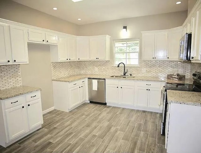 7090 Carroll Ln, Beaumont, TX 77713 - kitchen featuring stainless steel appliances, a sink, light stone counters, light wood finished floors, and recessed lighting