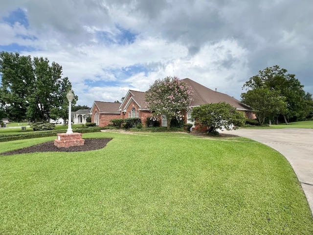 view of front of home with brick siding, concrete driveway, and a front yard