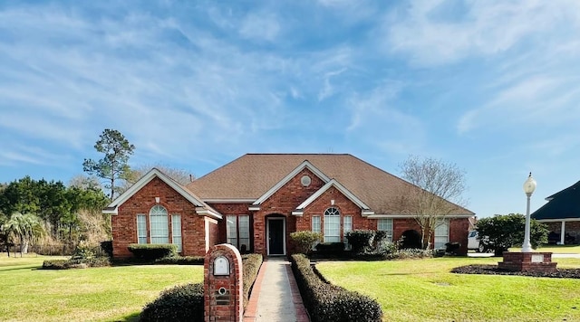 ranch-style home with brick siding, a front yard, and a shingled roof