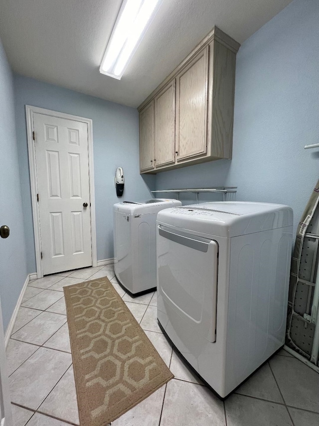 laundry room with cabinet space, washing machine and dryer, light tile patterned floors, and baseboards