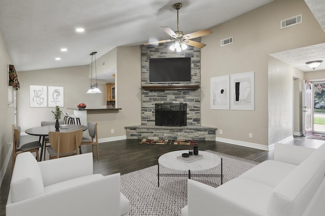 living room featuring dark hardwood / wood-style flooring, lofted ceiling, ceiling fan, and a fireplace