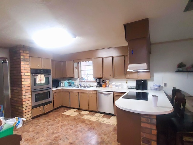 kitchen with a peninsula, a sink, extractor fan, light countertops, and appliances with stainless steel finishes