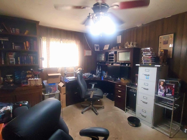 carpeted office space featuring wood walls and ceiling fan