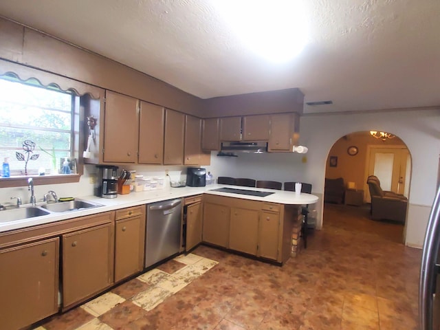 kitchen with light countertops, a sink, arched walkways, a peninsula, and appliances with stainless steel finishes