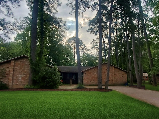 ranch-style house with a front lawn, brick siding, and driveway