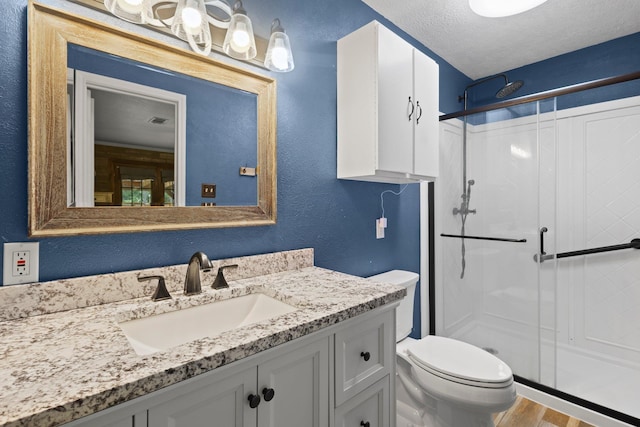 4169 Leatherwood Dr, Kountze, TX 77625 - bathroom featuring a stall shower, vanity, wood finished floors, a textured ceiling, and a textured wall