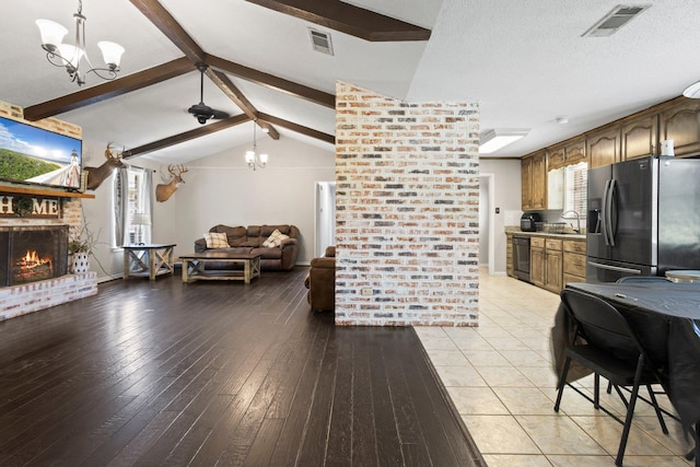 4169 Leatherwood Dr, Kountze, TX 77625 - kitchen with stainless steel fridge with ice dispenser, open floor plan, a chandelier, and a brick fireplace