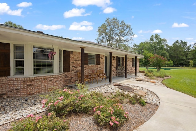 4169 Leatherwood Dr, Kountze, TX 77625 - view of side of home with brick siding, a porch, and a yard