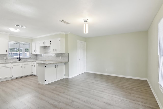 kitchen with light stone counters, light hardwood / wood-style flooring, tasteful backsplash, white cabinetry, and sink