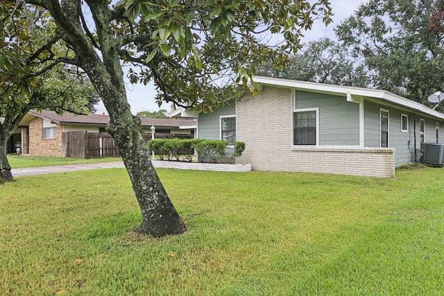 view of side of property featuring central air condition unit and a lawn