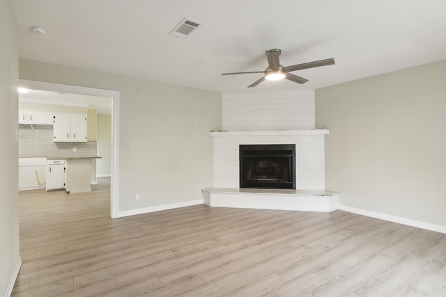 unfurnished living room with a fireplace, ceiling fan, and light hardwood / wood-style floors