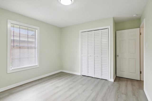 unfurnished bedroom with a closet and light hardwood / wood-style floors