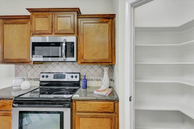 kitchen with tasteful backsplash, dark stone counters, and appliances with stainless steel finishes