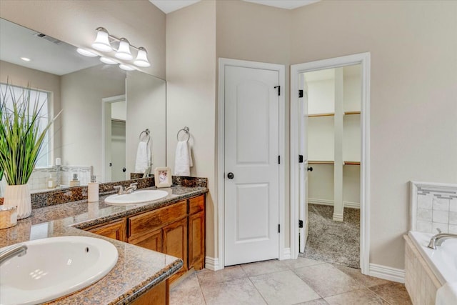 bathroom featuring tile patterned floors, tiled bath, and vanity