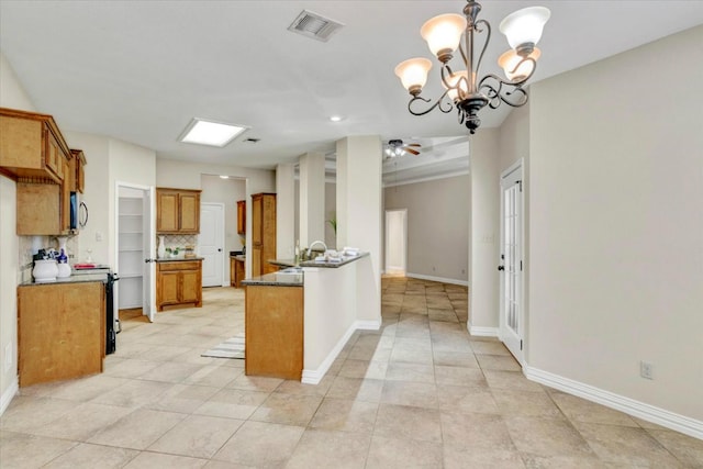 kitchen featuring ceiling fan with notable chandelier, tasteful backsplash, hanging light fixtures, and sink