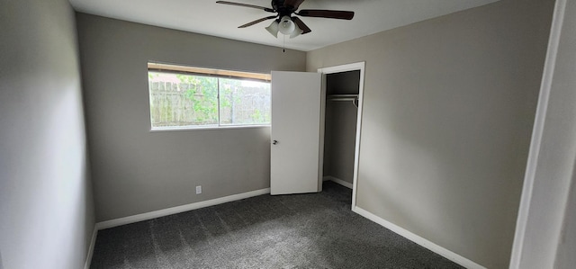 unfurnished bedroom with dark colored carpet, a closet, and ceiling fan