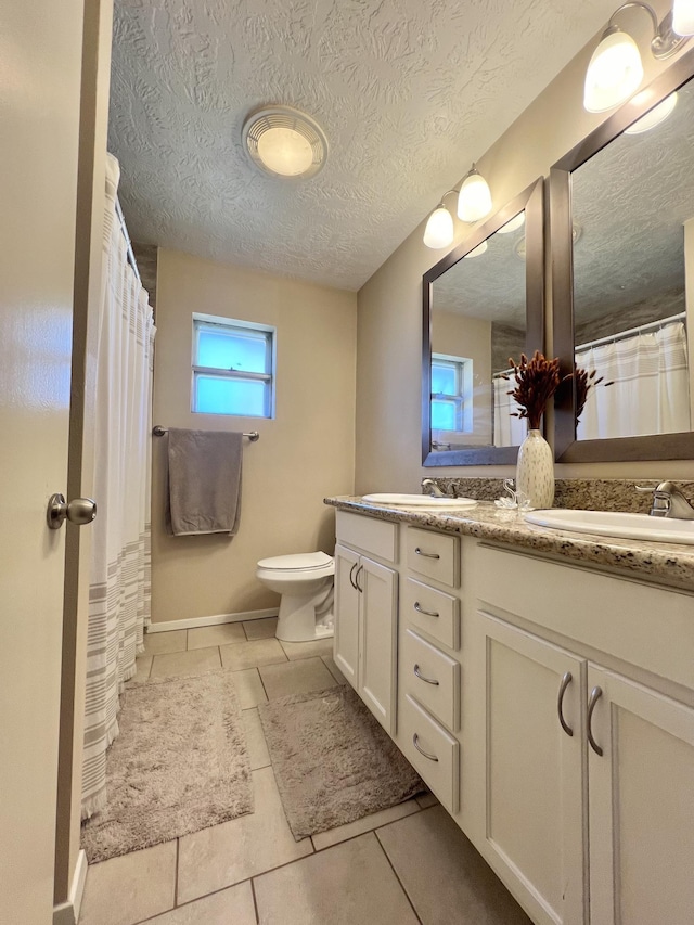 bathroom featuring tile patterned flooring, vanity, a textured ceiling, and toilet