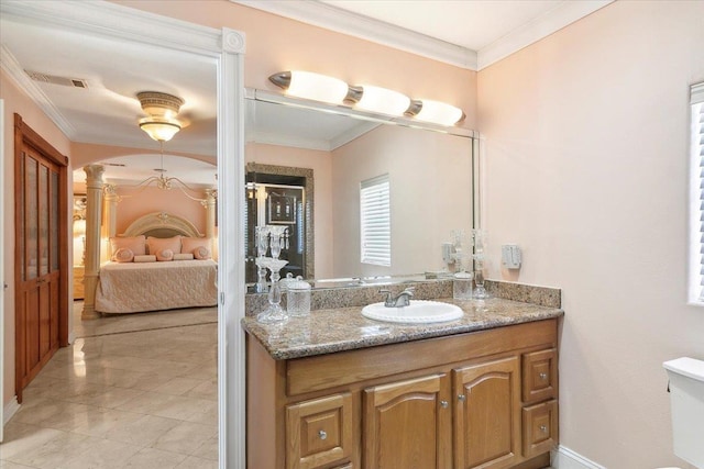 bathroom with ornate columns, vanity, and ornamental molding