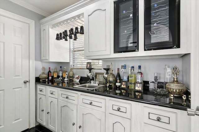 bar featuring white cabinetry, sink, and ornamental molding