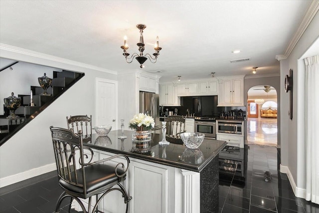 kitchen with a kitchen bar, white cabinets, stainless steel appliances, and an inviting chandelier