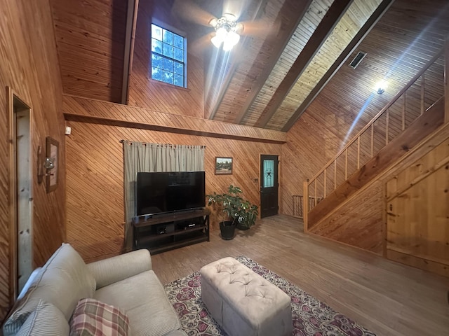 living area with wood finished floors, stairs, beamed ceiling, wooden ceiling, and wood walls