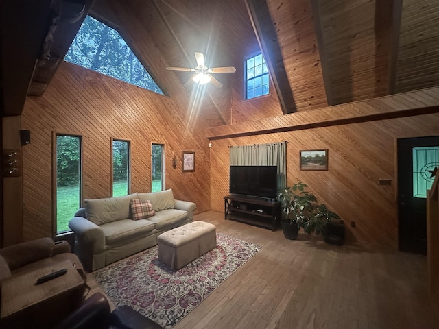 living area featuring hardwood / wood-style flooring, wood walls, high vaulted ceiling, and a ceiling fan