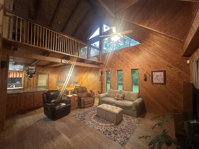 living area featuring wooden walls, wooden ceiling, wood-type flooring, high vaulted ceiling, and ceiling fan