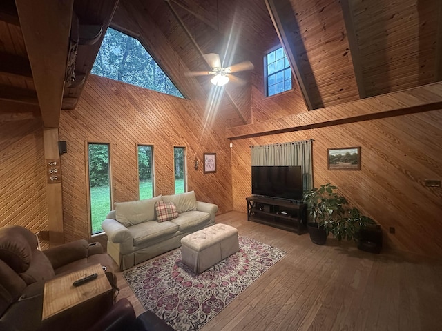 living room with high vaulted ceiling, a ceiling fan, wood ceiling, wood-type flooring, and wood walls