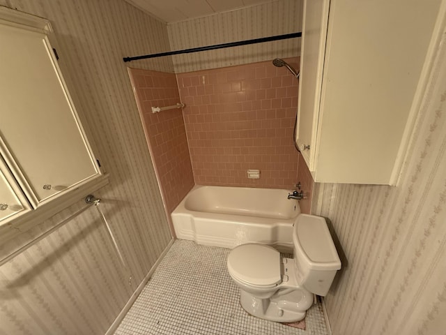 bathroom featuring tile patterned flooring, toilet, and tiled shower / bath