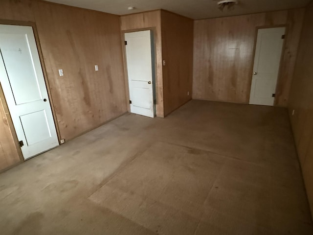 carpeted spare room with wooden walls