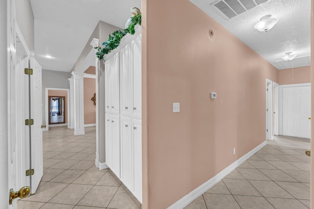 hall featuring light tile patterned floors and a textured ceiling