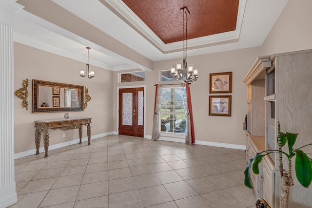 tiled foyer featuring a notable chandelier, french doors, ornamental molding, and a tray ceiling