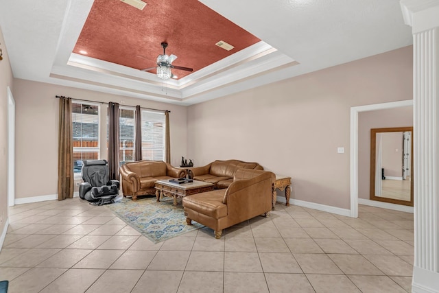 living room with a tray ceiling, ceiling fan, crown molding, and light tile patterned floors