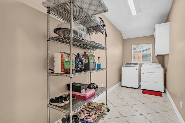 laundry room with washing machine and clothes dryer, light tile patterned flooring, and cabinets