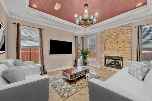 tiled living room with a fireplace, a healthy amount of sunlight, a raised ceiling, and crown molding