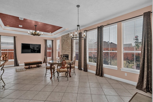 tiled dining space with a fireplace, a tray ceiling, an inviting chandelier, and a wealth of natural light