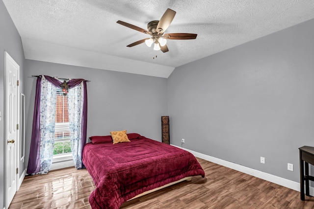 bedroom featuring a textured ceiling, ceiling fan, light hardwood / wood-style flooring, and lofted ceiling